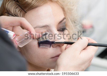 stylist paints eyelashes on one side of  face blonde