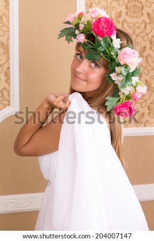 girl with wreath on his head on background of beige wall