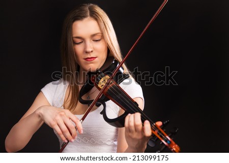Beautiful concentrated girl in white dress playing on electro violin