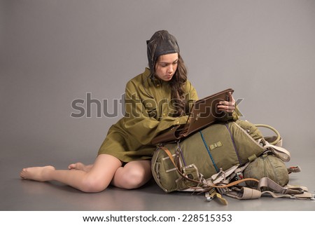 brunette  in uniform of the Soviet army and aviator cap sits on parachute and read
