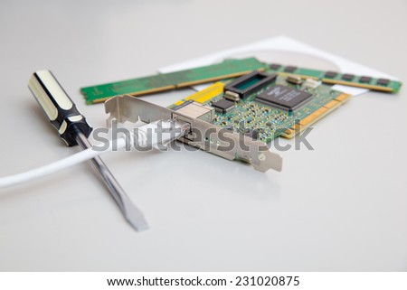 network card with cable, screwdrivers, RAM and disk On table
