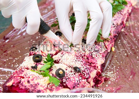 Hands in white  disposable gloves cut salad roll