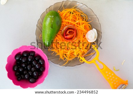 Straw carrot, avocado, rosette of apple and a plate of olives
