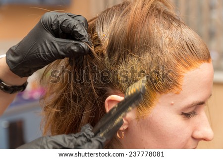 barber carefully paint the hair roots in red color