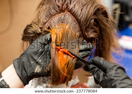 hairdresser dye the hair of girl in red color with special brush