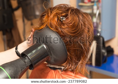 hairdresser dries the hair client hairdryer with special nozzle
