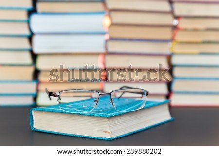 glasses lie on the blue book on a background pile of books