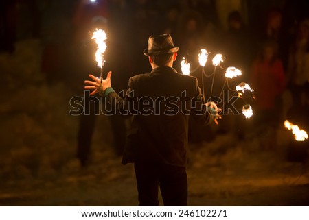 Perm, Russia - January 17, 2015. man with  fiery fan and fiery stick stands  his back