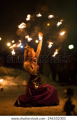 Perm, Russia - January 17, 2015. Woman in costume of queen with fiery fan under head stands on knee