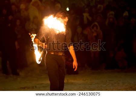 Perm, Russia - January 17, 2015. man twists fiery stick without hand on shoulder on show