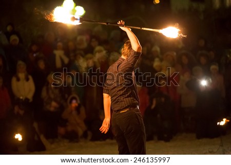 Perm, Russia - January 17, 2015. man in black suit holding fire stick over his head