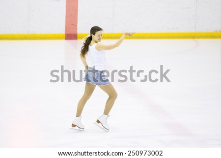 Perm, Russia - January 31, 2015. Figure skating competitions among fans. Girl in a denim skirt and white shirt dancing on ice skates