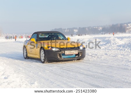 Dobryanka, Russia - February 7, 2015. Urban ice race. Yellow sport car comes in turn to snow sports track closeup