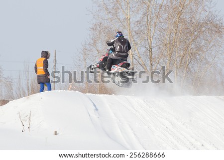 Perm, Russia - February 23, 2015. Championship on Cross Country Snowmobile. Man on snowmobile jumps over  hill on background of sky