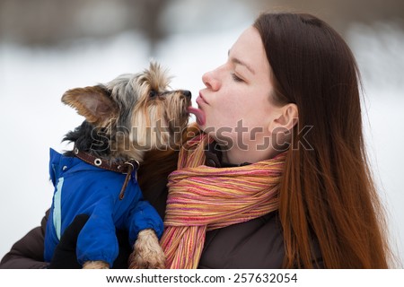 dog in blue overalls  licking face redhead girl