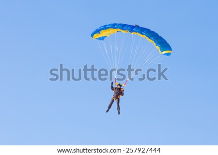 Skydiver on blue and yellow parachute