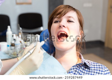 Drill in hand dentist and girl with mouth wide open