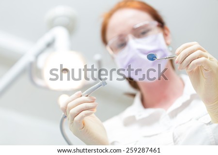 Drill and mirror in  hands of the dentist. Tools in Focus