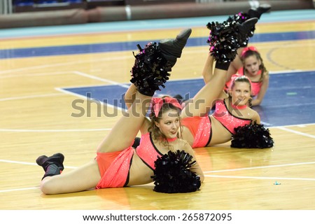Perm, Russia - March 28, 2015. Championship Perm Krai on cheerleading. Girl in pink costume making  split on floor with pom-poms cheerleading competitions