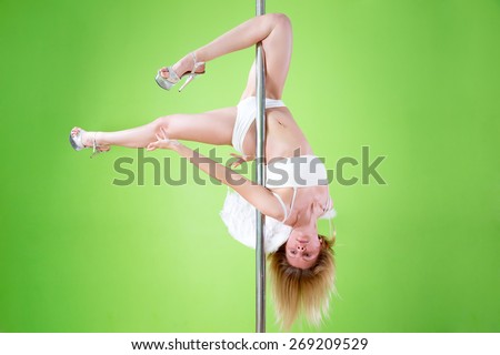 sexy girl in white shorts and angelic wings makes  element outer leg hold  at pole dance