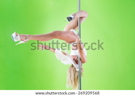 sexy girl in white shorts and angelic wings makes  element inner leg hold  at pole dance