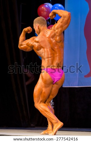 Perm, Russia - April 19, 2015.Cup Perm Krai  on bodybuilding and fitness bikini.  Muscular man in pink  briefs showing double biceps side view