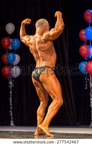 Perm, Russia - April 19, 2015.Cup Perm Krai  on bodybuilding and fitness bikini. Muscular man in black briefs showing double biceps from behind