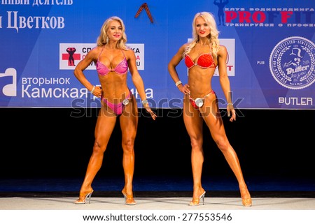 Perm, Russia - April 19, 2015.Cup Perm Krai  on bodybuilding and fitness bikini. Two blondes in red bikini posing facing the judges