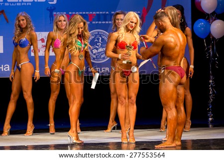 Perm, Russia - April 19, 2015.Cup Perm Krai  on bodybuilding and fitness bikini. Bodybuilder congratulates sexy blonde of competitions in fitness bikini