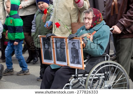 Perm, Russia - May 9, 2015. The parade dedicated to the 70th anniversary of the victory in the Second World War. An elderly woman in a wheelchair with portraits of their relatives