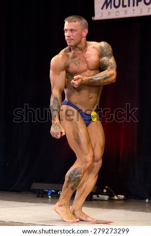 Izhevsk, Russia - April 18, 2015. Open championship of the Volga Federal District of bodybuilding and fitness bikini. Tattooed bodybuilder showing triceps and biceps