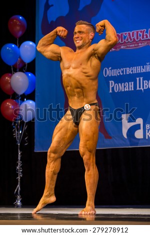 Perm, Russia - April 19, 2015.Cup Perm Krai  on bodybuilding and fitness bikini. Bodybuilder with a strained face shows the double biceps