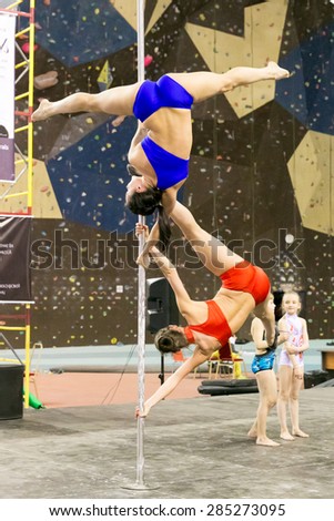 Perm, Russia - April 25, 2015. Championship Perm region at pole sport and dance. two girls in bright bathing suits make elements flag on one pole