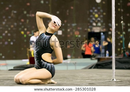 Perm, Russia - April 25, 2015. Championship Perm region at pole sport and dance. The brunette in a black suit covered her face with her hand