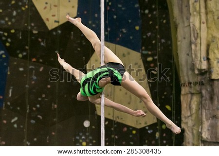 Perm, Russia - April 25, 2015. Championship Perm region at pole sport and dance. Girl in a black swimsuit with a green pattern making element Allegra