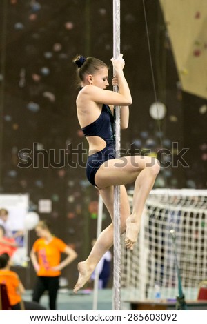 Perm, Russia - April 25, 2015. Championship Perm region at pole sport and dance. Girl in a black costume with a green pattern on climbs pylon