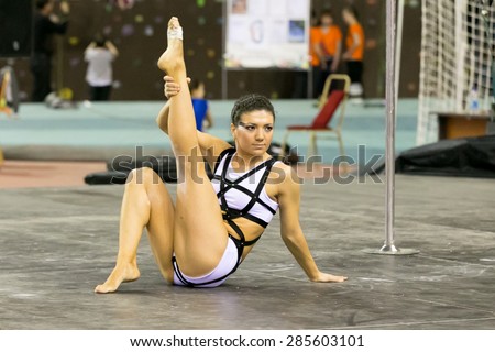 Perm, Russia - April 25, 2015. Championship Perm region at pole sport and dance. Young woman in a white suit with a black ribbon sitting on the floor lifted a leg up