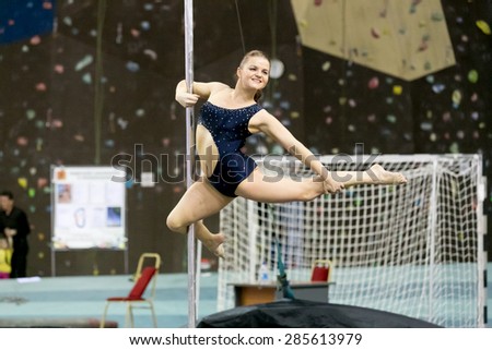 Perm, Russia - April 25, 2015. Championship Perm region at pole sport and dance. Smiling brunette in a black swimsuit making element  figure skater variations