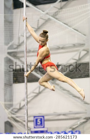 Perm, Russia - April 25, 2015. Championship Perm region at pole sport and dance. girl in an orange swimsuit makes the item twisted hold