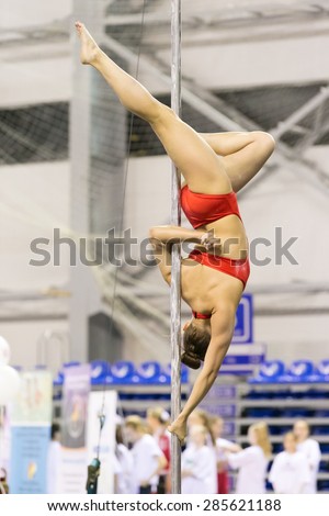Perm, Russia - April 25, 2015. Championship Perm region at pole sport and dance. girl in an orange swimsuit makes the item upside down