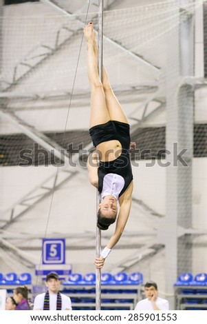 Perm, Russia - April 25, 2015. Championship Perm region at pole sport and dance. The brunette in a black costume  with a white collar does element shoulder flag