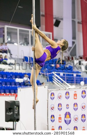 Perm, Russia - April 25, 2015. Championship Perm region at pole sport and dance. Brunette with a tress in purple costume making element diva onpole split