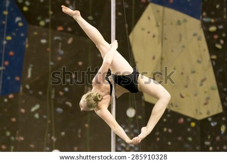Perm, Russia - April 25, 2015. Championship Perm region at pole sport and dance. little girl blonde in a black bathing suit makes the element allegra