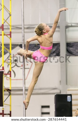 Perm, Russia - April 25, 2015. Championship Perm region at pole sport and dance. little girl in a pink swimsuit makes a element hook  of the knee