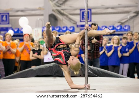 Perm, Russia - April 25, 2015. Championship Perm region at pole sport and dance.  blonde in a black swimsuit with a pink pattern makes element stand on the forearm