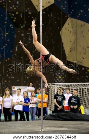 Perm, Russia - April 25, 2015. Championship Perm region at pole sport and dance. blonde in a black swimsuit with a pink pattern makes the element toe thigh