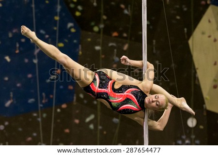 Perm, Russia - April 25, 2015. Championship Perm region at pole sport and dance.  blonde in a black swimsuit with a pink pattern makes the element Cheba split