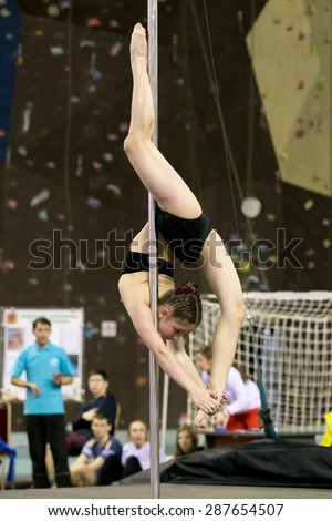 Perm, Russia - April 25, 2015. Championship Perm region at pole sport and dance. Small girl in black swimsuit makes deflection of Vis on the outside of the leg