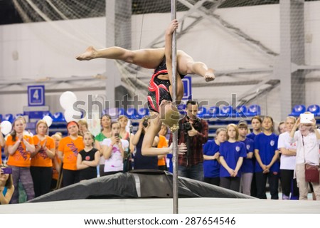 Perm, Russia - April 25, 2015. Championship Perm region at pole sport and dance. blonde in a black swimsuit with a pink pattern makes element  twisted grip straddle