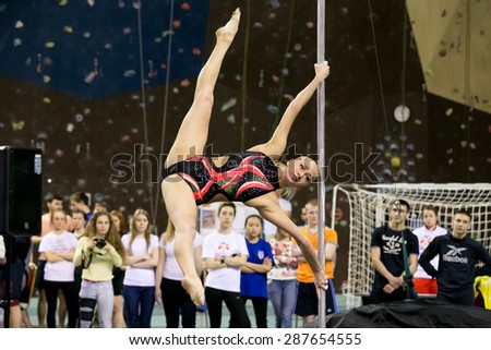 Perm, Russia - April 25, 2015. Championship Perm region at pole sport and dance. blonde in a black swimsuit with a pink pattern makes the element Twisted x-flag